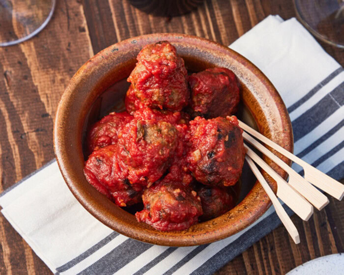 Delicious lamb meatballs with pine nuts and currants served in a rustic bowl, perfect for a flavorful appetizer or main dish.