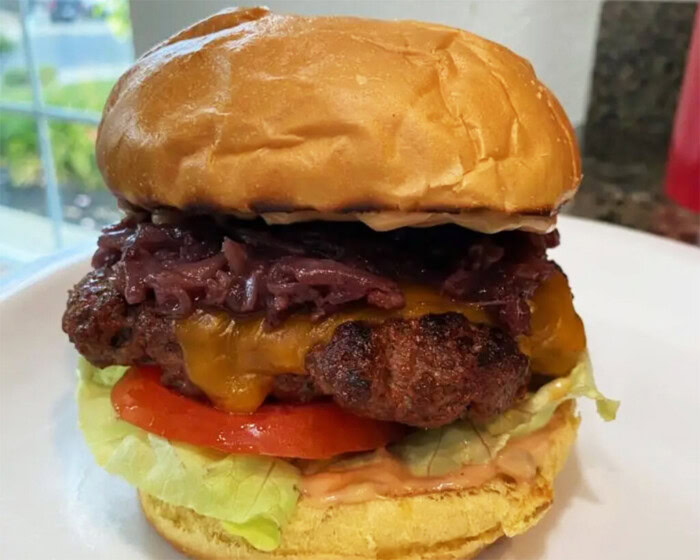 A delicious steakhouse cheeseburger with caramelized onions, lettuce, tomato, and melted cheese in a soft bun.