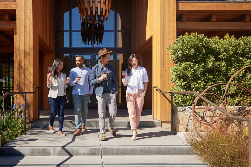 Group of four people walking out of Cakebread Cellars winery, enjoying wine tasting and conversation outdoors.
