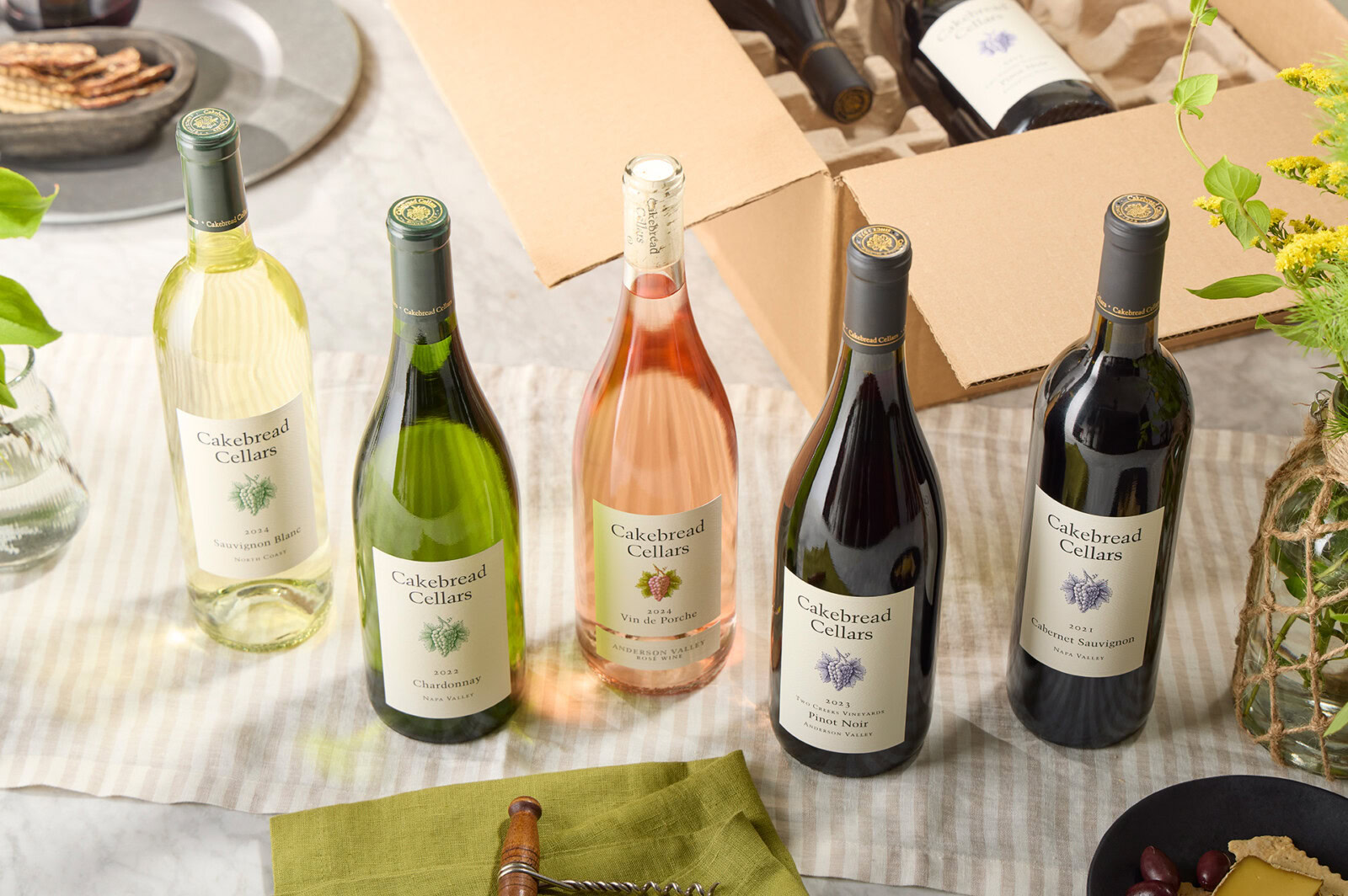 Collection of Cakebread Cellars wine bottles including white, rosé, and red wines on a table setting.