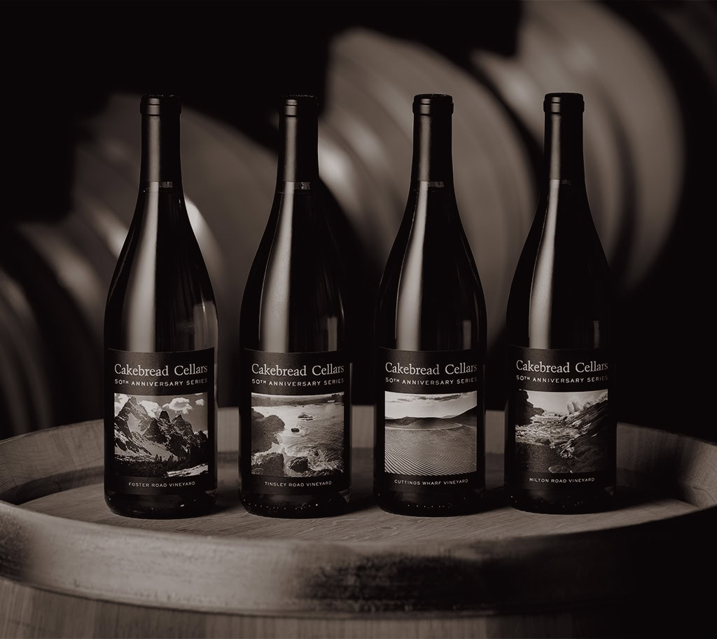 A bottle of Cakebread Cellars wine on a wooden surface with a blurred background.
