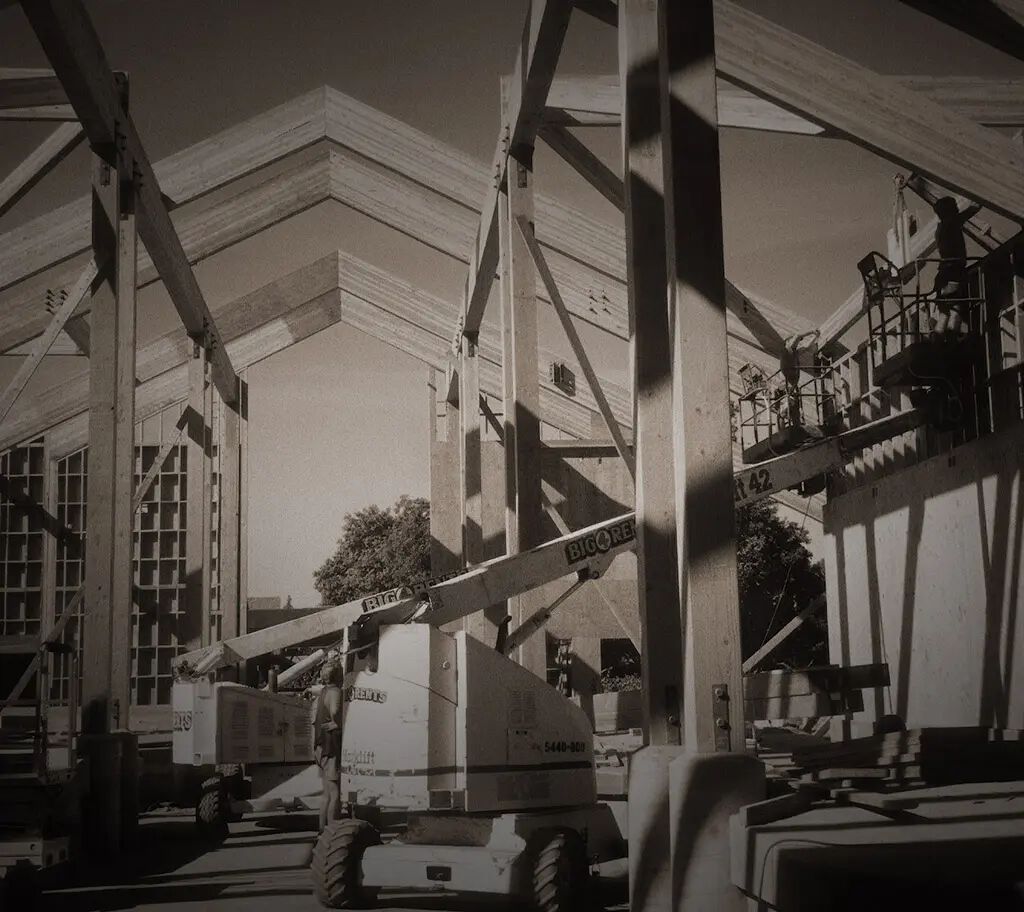Construction site of a building with scaffolding and a cherry picker, showing ongoing structural work at the winery.