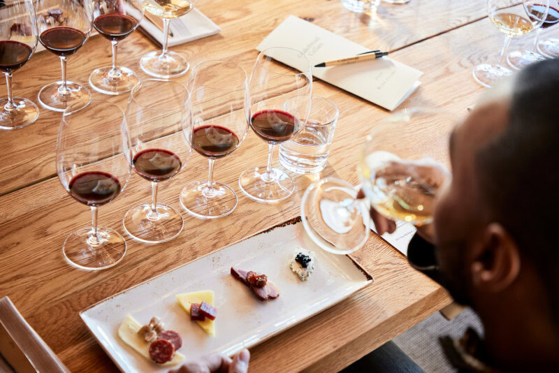 Tasting wine at Cakebread Cellars with multiple glasses of red wine on a wooden table.