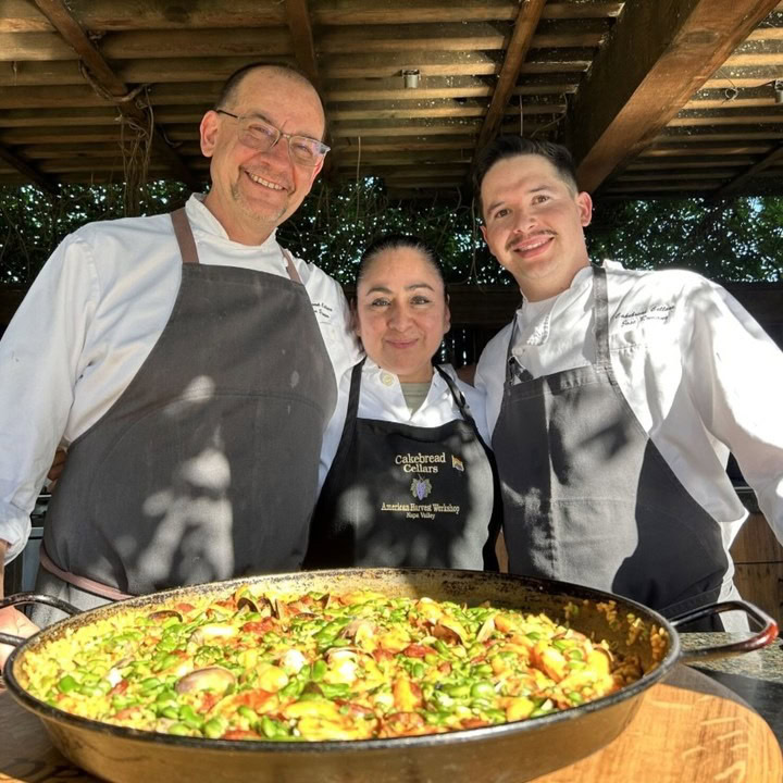Freshly cooked paella with chefs from Cakebread Cellars, showcasing culinary expertise and fresh ingredients in an outdoor se.