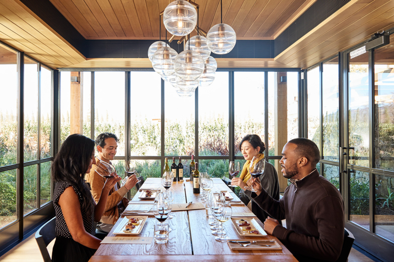 Four people sitting at a table in a room with lots of windows